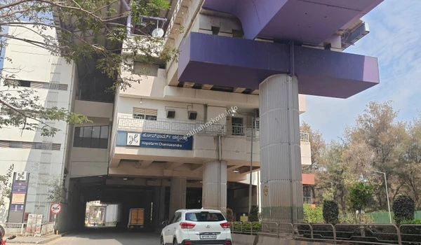Exterior architecture of the Hopefarm Channasandra metro station showing the elevated purple support beams, concrete pillars, and the station signboard in Kannada and English.