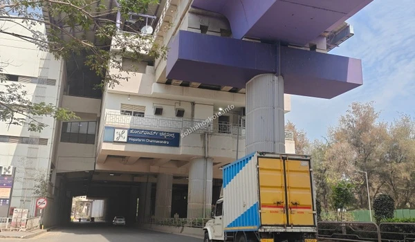 Modern architectural design of an elevated Namma Metro station in Bengaluru, showing the concrete pillars, purple-themed tracks, and street-level traffic.