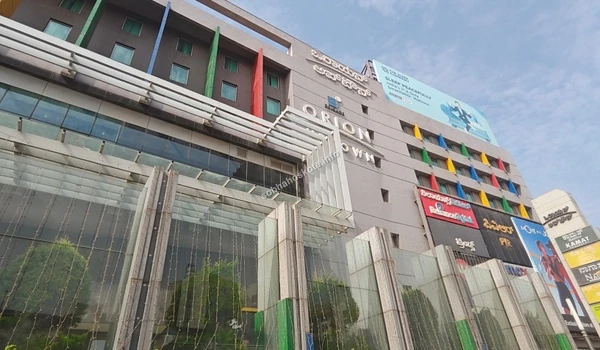 A wide-angle view of the Orion Uptown Mall building facade near Sobha Hoskote showcasing retail outlets and proximity to the residential area