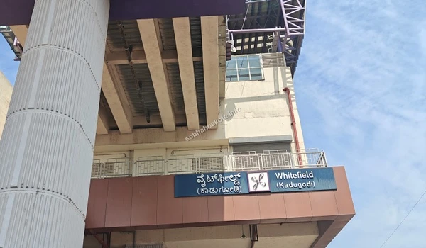 A daytime view of the Hopefarm Channasandra metro station building, highlighting the signage and the elevated purple line infrastructure in Whitefield.