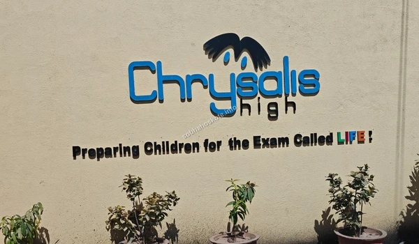 The prominent signage of Chrysalis High near Sobha Hoskote emphasizing their mission of preparing children for the exam called life through quality education