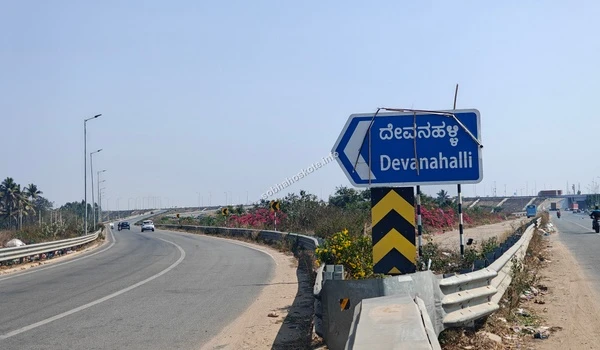 Large blue overhead directional board on the Satellite Town Ring Road (STRR) near Sobha Hoskote indicating routes to Devanahalli, Dabaspete, and the International Airport
