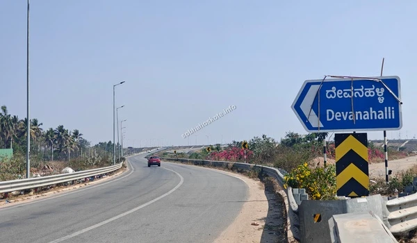 A perspective of the STRR highway lanes and palm-lined surroundings heading toward Devanahalli from the Hoskote area infrastructure