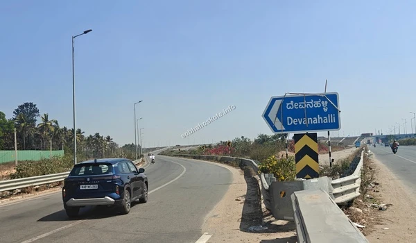 Large blue overhead signage on the Satellite Town Ring Road (STRR) near Sobha Hoskote providing clear navigation to Devanahalli, Dabaspete, and the International Airport