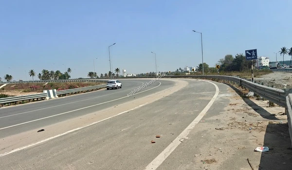 A white car traversing the Satellite Town Ring Road (STRR) near Sobha Hoskote, demonstrating the active and smooth traffic flow of the new expressway